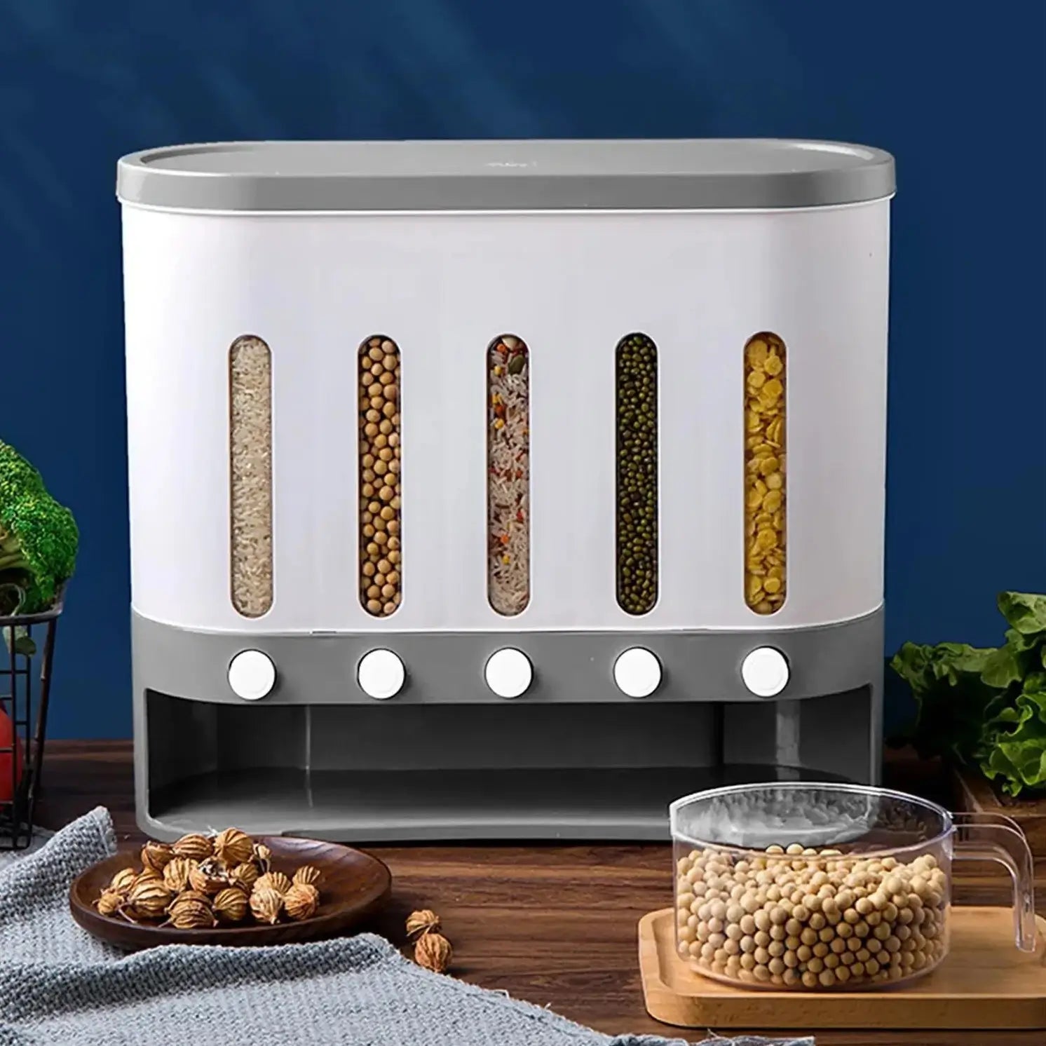 The Cereal Dispenser with its 5 grids full, resting on a wooden surface In front of a blue wall, surrounded by condiments.