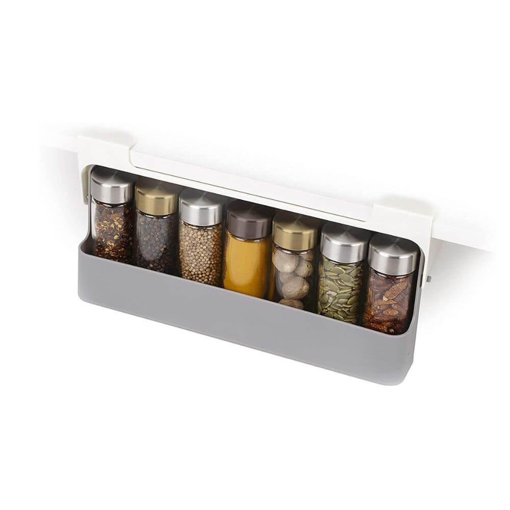 The cupboard spice rack organiser set full with jars containing various herbs, with a white background