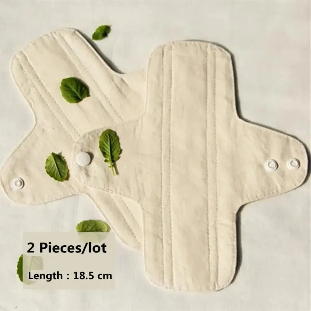 Two opened Reusable Sanitary Pads with tiny leaves resting on and around the pad.