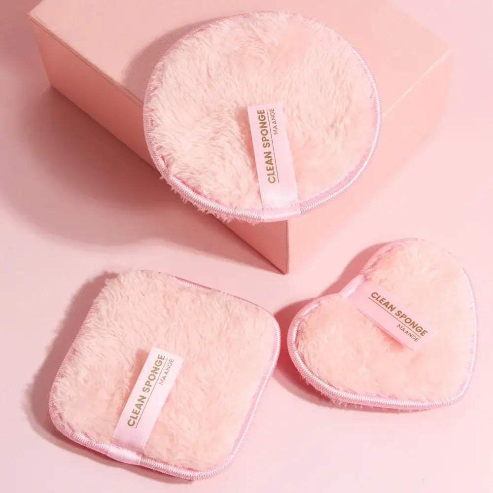 The 3 reusable makeup remover pads. 2 on the floor and 1 on a pink box, with a pink background.